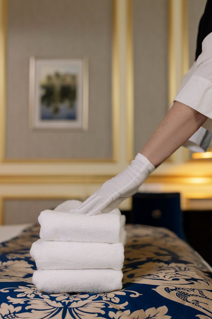 journey-01 A hotel housekeeper in uniform arranges freshly laundered towels in a luxurious room.